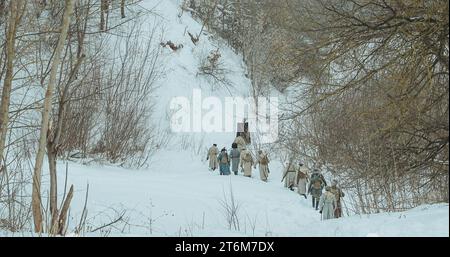 Uomini vestiti da soldati della Guardia Bianca dell'Esercito Imperiale Russo in marcia nella Foresta invernale innevata della Guerra civile russa. Rievocazione storica di Foto Stock