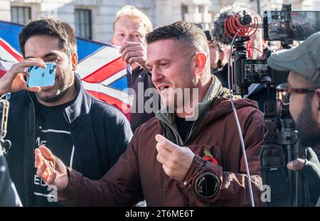 Londra, Regno Unito. 11 novembre 2023. Stephen Yaxley-Lennon (alias Tommy Robinson) lascia Whitehall dopo la cerimonia del giorno dell'armistizio al Ceotaph, circondato da sostenitori, alcuni indossano maschere e portano bandiere sindacali credito: Phil Robinson/Alamy Live News Foto Stock