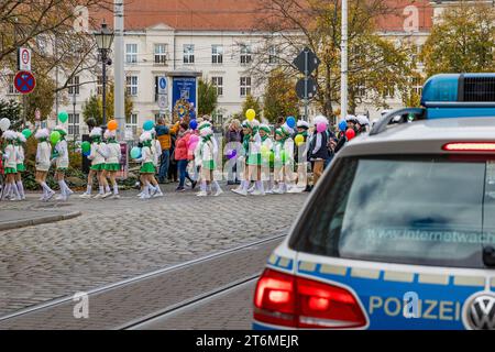 11 novembre 2023, Brandeburgo, Cottbus: I festaioli del Carnevale, sorvegliati dalla polizia, si dirigono al municipio di Cottbus, dove vogliono prendere le chiavi della città in un assalto simbolico al municipio. Foto: Frank Hammerschmidt/dpa Foto Stock