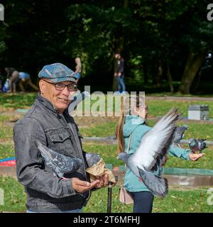 Uomo e giovane ragazza che danno da mangiare ai piccioni nel parco Foto Stock