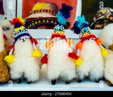 Fila di peluche di alpaca con cappelli tradizionali color arcobaleno, mercato tradizionale di Pisac, Perù Foto Stock