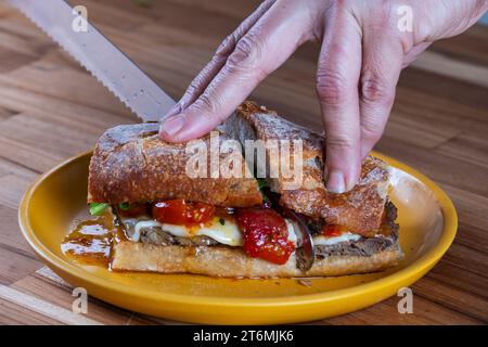 delizioso panino con arrosto di manzo, mozzarella di bufala, cipolla rossa caramellata e rucola. Foto Stock