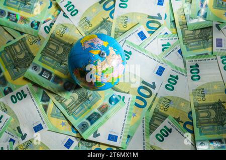 Un piccolo giro globus visto dall'alto su molte banconote, 100 banconote in euro. Foto di alta qualità Foto Stock