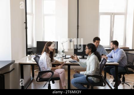 Coppie di colleghi di ufficio multietnici impegnati che parlano in un luogo di lavoro condiviso Foto Stock