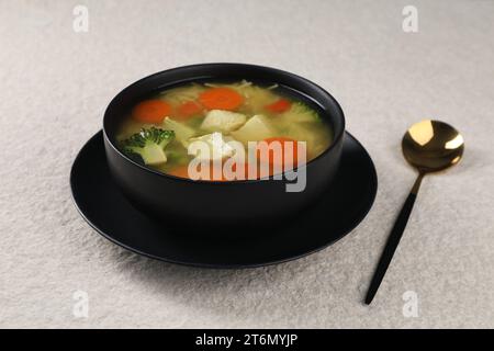 Gustosa zuppa di pollo con spaghetti e verdure in ciotola servita su un tavolo leggermente ruvido Foto Stock
