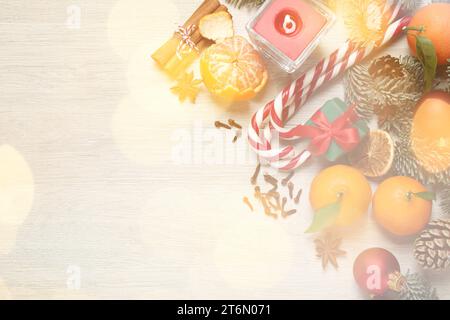 Bella composizione natalizia con canne caramelle, mandarini e spazio per il testo su un tavolo di legno bianco, posato piatto. Effetto bokeh Foto Stock
