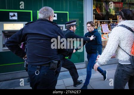 Londra, Regno Unito, 11 novembre 2023. Un uomo viene allontanato dalla polizia dopo che un sostenitore pro-palestinese è stato aggredito. L'incidente accadde dopo che un piccolo gruppo lasciò il cenotafio e si scontrò con una marcia in Palestina. Tommy Robinson ha espresso il motivo per scoraggiare qualsiasi manifestante pro-palestinese che potrebbe voler marciare attraverso Whitehall durante il weekend della memoria. Questo arriva dopo cinque settimane consecutive di proteste per fermare la guerra a Gaza.ÊAndy Barton / Alamy Live News Foto Stock