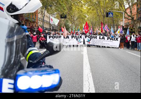 Tolosa, Francia. 11 novembre 2023. La CGT, la F.S.U, la LFI e altri partiti di sinistra dietro lo striscione, for Peace, Stop the massacre a Gaza !la Francia deve chiedere un cessate il fuoco immediato, con un poliziotto su una moto in primo piano. Manifestazione per la pace a Gaza, contro i massacri e richiesta di un immediato cessate il fuoco. Sono presenti varie unioni, tra cui CGT, F.S.U le NPA, LFI e vari collettivi palestinesi, tra cui Collectif Palestine Vaincra. Francia, Tolosa 11 novembre 2023. Foto di Patricia Huchot-Boissier/ABACAPRESS. Credito: Abaca Press/Alamy Live News Foto Stock