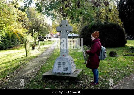 donna in 2 minuti di silenzio accanto a una croce commemorativa per il giorno del papavero, le grandi guerre Foto Stock