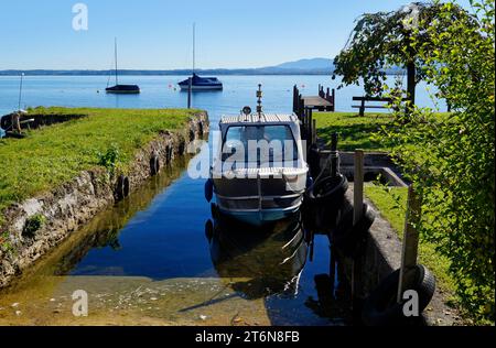 Una vista panoramica con una vecchia barca da pesca sull'isola Frauenchiemsee o Fraueninsel sul lago Chiemsee in una soleggiata giornata di ottobre in Baviera (Germania) Foto Stock