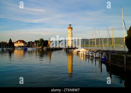 Porto illuminato dal sole e faro di Lindau sul tranquillo lago Costanza (lago Bodensee) con le Alpi sullo sfondo in una calda e soleggiata serata in ottobre Foto Stock