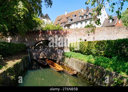 Una vista panoramica di un piccolo ponte, barche di legno (Ulmer Schachteln) sotto di esso, alberi verdi e le mura della città vecchia nella città di Ulm in Germania Foto Stock