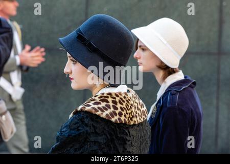 New York City, NY – 11 novembre 2023. L'annuale Veterans Day Parade radunò veterani americani, veterani stranieri e loro sostenitori per marciare sulla Fifth Avenue. Due donne in abiti d'epoca e cappelli cloche accompagnano i reenattori della prima guerra mondiale dei Doughboys della East Coast. Foto Stock