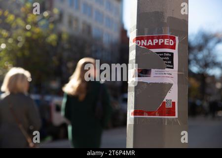 I pedoni che camminano accanto ai poster "rapiti" abbattuti, che mostrano gli ostaggi tenuti da Hamas, a Boston, Massachusetts, l'11 novembre 2023. Dall'attacco del 7 ottobre 2023, Hamas ha tenuto oltre 200 ostaggi. Da allora i manifestanti sono diventati bersagli per i manifestanti, che li deturpano o li distruggono. Foto Stock