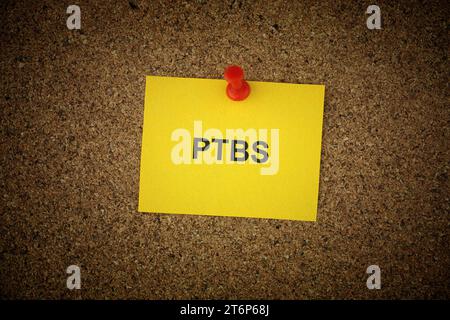 Una nota di carta gialla con l'abbreviazione PTBS - disturbo da stress posttraumatico (in tedesco) apposta su di essa su una tavola di sughero. Primo piano. Foto Stock