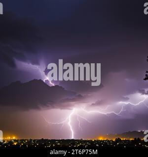 Immagine drammatica di un fulmine che colpisce un albero alto contro un cielo notturno scuro, creando una vista potente e impressionante Foto Stock
