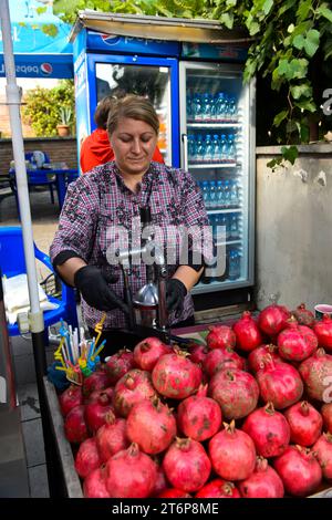 La donna prepara il succo di melograni (Punica granatum) in uno stand nella città vecchia di Tbilisi, Tblisi, Georgia Foto Stock