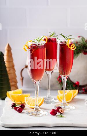 Mimosa natalizia con succo di mirtilli rossi e champagne o vino frizzante, cocktail natalizi festivi guarniti con scorza d'arancia Foto Stock