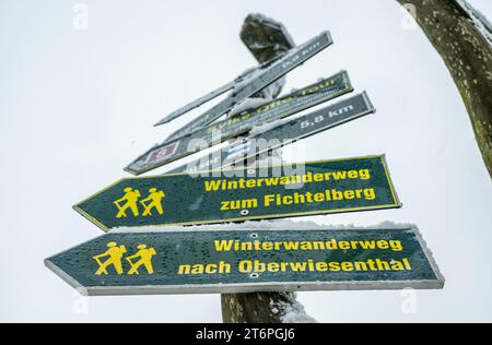 11 novembre 2023, Sassonia, Oberwiesenthal: Un sottile strato di neve può essere visto sui cartelli escursionistici di Oberwiesenthal. I primi fiocchi di neve caddero la mattina. Tuttavia, poiché il terreno è ancora caldo, lo splendore bianco non rimarrà a lungo. Foto: Kristin Schmidt/dpa-Zentralbild/dpa Foto Stock