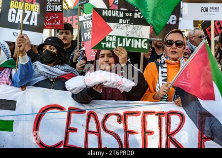 11 novembre 2023, Londra, Regno Unito. Centinaia di migliaia di persone marciano attraverso il centro di Londra per protestare contro il continuo bombardamento di Gaza da parte di Israele. Gli organizzatori della manifestazione, la Palestina Solidarity Campaign, chiedono un cessate il fuoco immediato. Nella foto: Una donna a capo della marcia tiene un cadavere simbolico per rappresentare coloro che sono stati uccisi durante il bombardamento di Gaza. Foto Stock