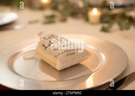 Borsa a tela con la scritta "Let Love Brew", un pezzo del centro per matrimoni, riempito di macine di cofee sul tavolo della cena Foto Stock