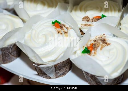 Torte di cioccolato con turbolenza di rasberry e frutta di rasberry su cupcake con glassa alla vaniglia e condimenti di carote sul tavolo del dessert Foto Stock