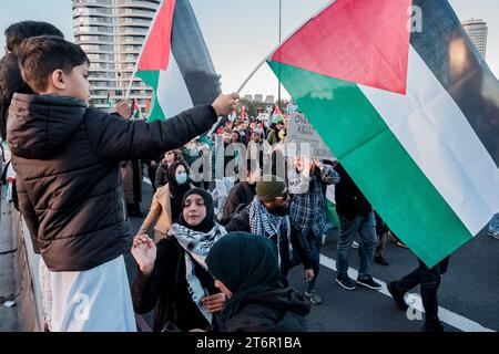 11 novembre 2023, Londra, Regno Unito. Centinaia di migliaia di persone marciano attraverso il centro di Londra per protestare contro il continuo bombardamento di Gaza da parte di Israele. Gli organizzatori della manifestazione, la Palestina Solidarity Campaign, chiedono un cessate il fuoco immediato. Nella foto: Un giovane ragazzo sventola una bandiera palestinese mentre i manifestanti marciano verso una manifestazione vicino all'ambasciata americana. Foto Stock