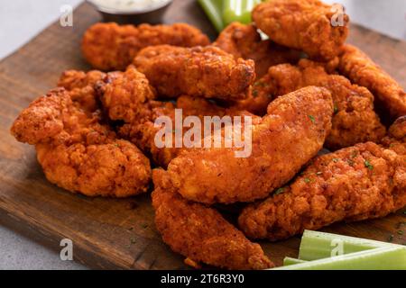 Strisce di pollo fritte di bufala su una tavola con ranch e bastoncini di sedano Foto Stock