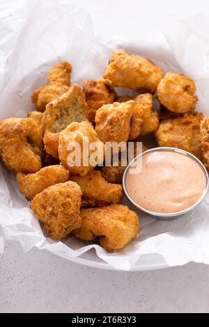 Pepite fritte di pesce gatto in una ciotola con salsa Foto Stock