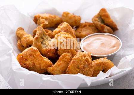 Pepite fritte di pesce gatto in una ciotola con salsa Foto Stock