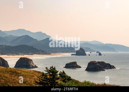 Una vista dall'Ecola State Park, Oregon, verso Cannon Beach con l'iconica Haystack Rock e le aspre colline della costa dell'Oregon oltre. Foto Stock