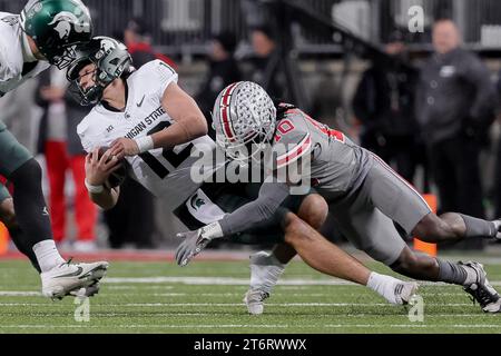 12 novembre 2023, Columbus, Ohio, Stati Uniti: Il quarterback dei Michigan State Spartans Katin Houser (12) viene placcato per una sconfitta dal cornerback degli Ohio State Buckeyes Denzel Burke (10) durante la partita tra i Michigan State Spartans e gli Ohio State Buckeyes all'Ohio Stadium, Columbus, Ohio. (Immagine di credito: © Scott Stuart/ZUMA Press Wire) SOLO USO EDITORIALE! Non per USO commerciale! Foto Stock