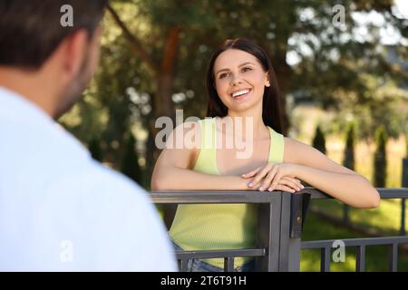 Rapporto amichevole con i vicini. Donna e uomo felici vicino alla recinzione all'aperto Foto Stock