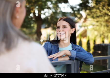 Rapporto amichevole con i vicini. Donne felici vicino alla recinzione all'aperto Foto Stock