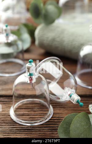 Coppe in plastica su tavolo in legno, primo piano. Terapia di coppettazione Foto Stock