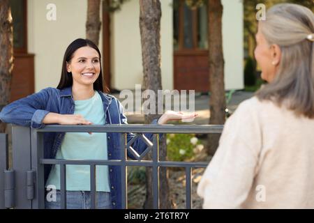 Rapporto amichevole con i vicini. Donne felici vicino alla recinzione all'aperto Foto Stock