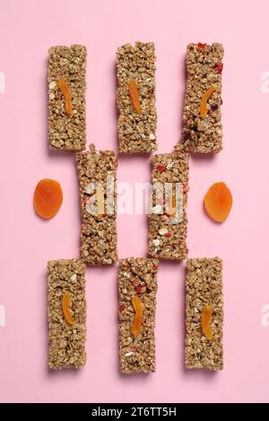 Gustose barrette di muesli su sfondo rosa, distese piatte Foto Stock