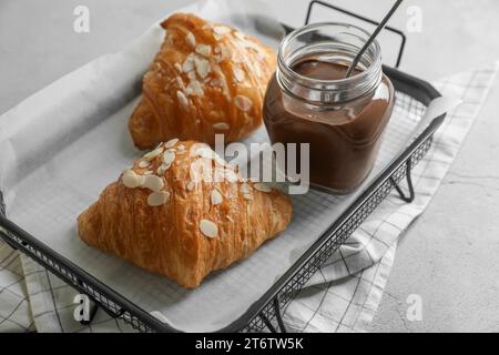 Croissant deliziosi con fiocchi di mandorle e pasta di cioccolato su tavolo grigio chiaro, primo piano Foto Stock