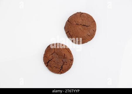 Due biscotti al cioccolato appena sfornati con un ripieno cremoso di burro di arachidi, presentati su uno sfondo bianco Foto Stock