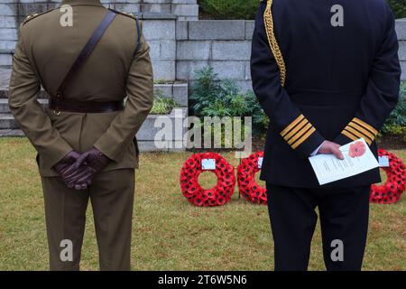 Gli uomini in uniforme militare tengono un programma per le cerimonie della domenica della memoria al cimitero di Hodagaya Commonwealth War Graves a Yokohama. Quest'anno l'ambasciata neozelandese ha ospitato questo evento commemorativo che segna la fine della prima guerra mondiale e onora tutti coloro che sono morti in servizio militare. Foto Stock