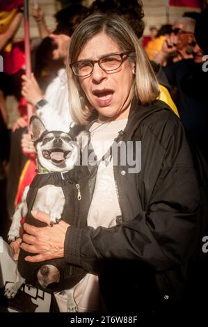 Barcellona, Spagna. 12 novembre 2023. 12 novembre 2023, Barcellona, Spagna: Nel centro di Barcellona una donna che tiene un cane grida slogan mentre la gente si riunisce per protestare contro l'accordo tra il partito socialista spagnolo e l'ex presidente catalano Carles Puigdemont per concedere l'amnistia ai separatisti catalani in cambio del sostegno al nuovo governo spagnolo. Credito: Jordi Boixareu/Alamy Live News Foto Stock