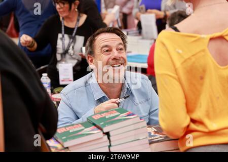 Brive-la-Gaillarde, Francia. 12 novembre 2023. Michel Bussi scrittore francese di successo dedica i suoi libri alla famosa fiera del libro di Brive (Foire du livre de Brive). Michel Bussi ha una carriera letteraria di grande importanza, in particolare nel campo dei romanzi polizieschi. È uno degli scrittori francesi più venduti. I romanzi di Michel Bussi sono tradotti in più di 35 lingue e sono particolarmente popolari nel Regno Unito, Italia, Cina, Brasile, Russia... Brive-la-Gaillarde, Corrèze, Francia, Europa. Foto HM Images/Alamy Live News. Foto Stock