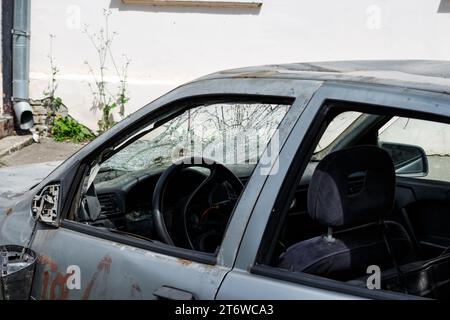 Una vecchia vettura con parabrezza rotto e tracce di atti vandalici sulla carrozzeria, uno specchietto retrovisore rotto Foto Stock