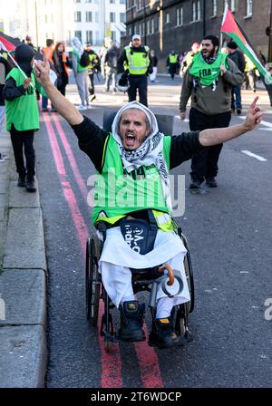 Uomo su sedia a rotelle che partecipa a una marcia pro-palestinese che chiede un cessate il fuoco a Gaza attraverso Londra il giorno dell'armistizio dell'11 novembre 2023. Foto Stock