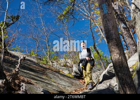 Una donna cinese sul sentiero delle scogliere whitestone che conduce su un pendio roccioso a plymouth, connecticut, in una soleggiata giornata di cielo blu. Foto Stock