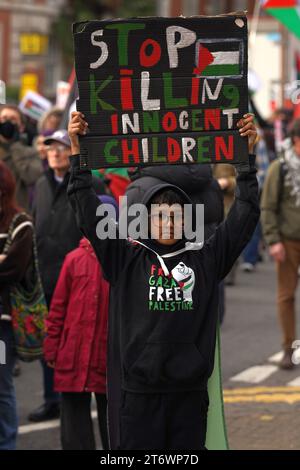 Bambino che tiene in piedi uno striscione stop Killing Children alla marcia pro Palestina nel centro di Cardiff, sabato 11 novembre 2023 Foto Stock