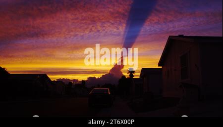 L'ombra nuvola con gli ingredienti meteorologici perfetti crea un tramonto ultraterreno su questo quartiere non descritto. Foto Stock