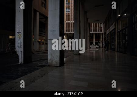 Mantova, Italia - ottobre 2023 - Porchway al limitare di un viale con negozi e gente che passa in una città italiana al tramonto Foto Stock