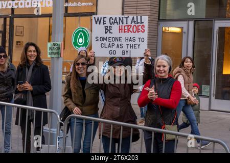 NEW York, NEW YORK - 11 NOVEMBRE: Gli spettatori tengono segno e bandiere nell'annuale Veterans Day Parade dell'11 novembre 2023 a New York City. Centinaia di persone hanno percorso la 5th Avenue per assistere alla più grande parata del Veterans Day degli Stati Uniti. Questo evento di quest'anno comprendeva veterani, soldati attivi, agenti di polizia, vigili del fuoco e dozzine di gruppi scolastici che partecipavano alla sfilata che onora gli uomini e le donne che hanno servito e sacrificato per il paese. Foto Stock