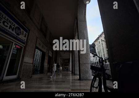 Mantova, Italia - ottobre 2023 - Porchway al limitare di un viale con negozi e gente che passa in una città italiana al tramonto Foto Stock